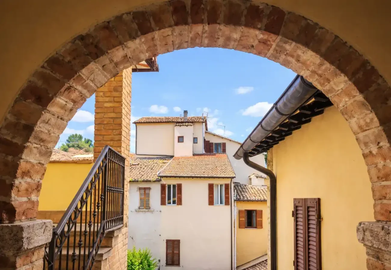Vista del centro storico di Ascoli Piceno attraverso arco in pietra con case tipiche